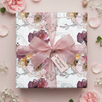 Elegant floral wrapping paper on a gift box with a pink sheer ribbon and roses.
