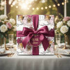 Elegant floral wrapping paper with burgundy ribbon and "With Love" tag on a gift at a formal place setting.
