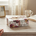 Elegant gift wrapped in floral wrapping paper with twine ribbon on a wooden table.