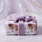 Elegant floral wrapping paper with soft purple plush bow and ribbon.