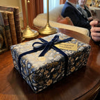 Elegant Wrapped Studios gift in dark floral wrapping paper with a velvet navy ribbon.