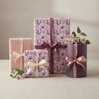 Elegant gifts wrapped in mauve floral wrapping paper with ribbons, perfect for birthdays or special occasions.