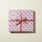 Square gift wrapped in floral wrapping paper with a rose ribbon and bow.