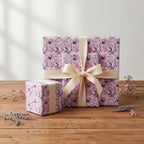 Three gifts wrapped in purple floral wrapping paper with cream ribbon.