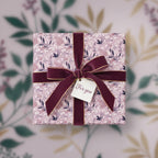 Elegant square gift wrapped in floral wrapping paper with burgundy velvet ribbon and "For You" tag.