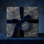 Luxury gift wrap with gold swirl pattern, dark blue velvet ribbon, and "With Love" tag. Wrapped Studios.