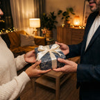 Hands exchange gift with blue patterned wrapping paper and ivory satin ribbon.