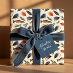 Fly fishing wrapping paper with watercolor trout, blue velvet ribbon, and adventure gift tag by Wrapped Studios.
