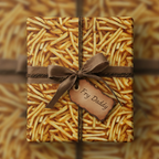 Fry Daddy novelty gift wrap on a square box with brown ribbon and twine.
