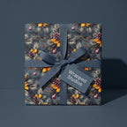 Wrapped Studios elegant Christmas gift wrap. Blue ribbon on box with pinecone, berry, and ornament design.