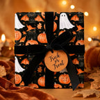 Spooky Halloween wrapping paper with cats, ghosts, and pumpkins, with a black velvet bow by Wrapped Studios.