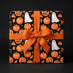 Spooky pumpkin and ghost Halloween wrapping paper on a gift box with an orange bow by Wrapped Studios.