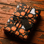Halloween wrapping paper with pumpkins and ghosts, tied with black twine by Wrapped Studios.