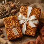 Unique yellow seed patterned wrapping paper with cream ribbon and twine on rustic wood background.