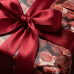 Burgundy ribbon adorns a gift wrapped in unique meat print paper.