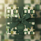 Retro gift box with green geometric wrapping paper and matching bow.