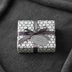 Modern black and white bubble pattern gift wrap with grey ribbon and "For You, With Love" tag on a dark grey background.
