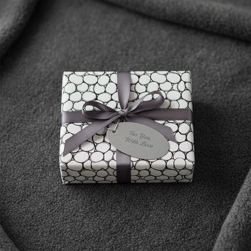 Modern black and white bubble pattern gift wrap with grey ribbon and "For You, With Love" tag on a dark grey background.