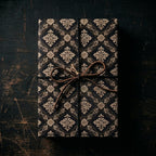 Vintage black and gold damask wrapping paper on a rustic gift box with a leather bow by Wrapped Studios.