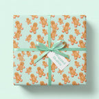 Cute gingerbread Christmas wrapping paper by Wrapped Studios on a gift box with a mint green ribbon.