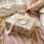 Gingerbread Christmas wrapping paper with cream ribbon in a cozy holiday setting by Wrapped Studios.