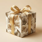 Luxury gold ginkgo leaf wrapping paper on a gift box with a satin bow by Wrapped Studios.