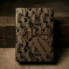 Geeky circuit board gift wrap in black and gold with a rustic twine bow, by Wrapped Studios.