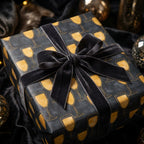 Luxury champagne gift wrap in black and gold with a velvet bow by Wrapped Studios.
