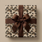 Luxury botanical ginkgo leaf wrapping paper with a brown ribbon bow on a square gift box, by Wrapped Studios.