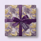 Elegant gold and purple swirl pattern wrapping paper with satin ribbon bow. Wrapped Studios.