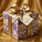 Elegant gift box wrapped in swirling gold and purple luxury wrapping paper, tied with a gold satin ribbon.