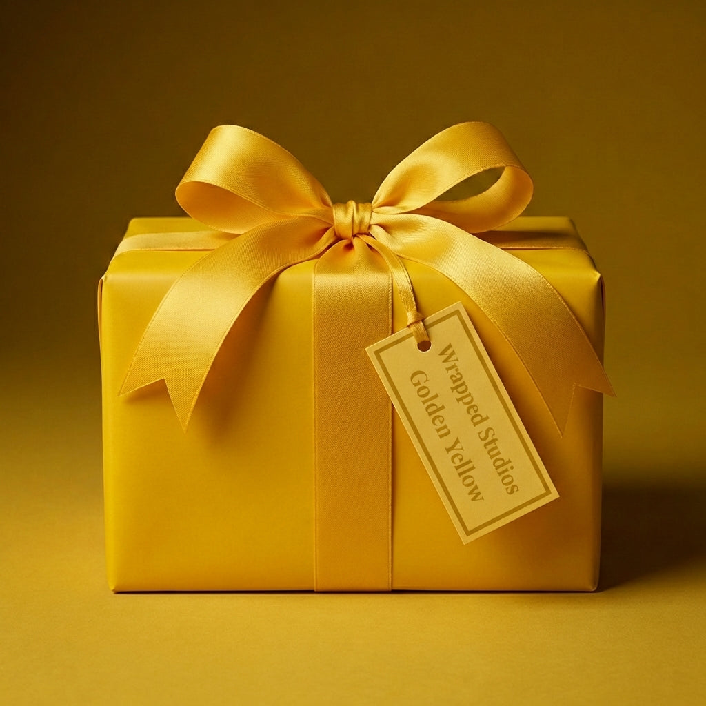 Golden yellow gift box mockup wrapped in solid color paper with satin bow and branded gift tag.