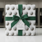 Gift box wrapped in golf ball wrapping paper with a green ribbon and "For the Champion" tag.