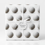 Golf ball wrapping paper from Wrapped Studios tied with a white ribbon and gift tag.