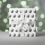 Wrapped Studios golf ball wrapping paper, tied with a white satin bow.