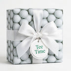 Golf wrapping paper with a white satin bow and Tee Time tag on a gift box by Wrapped Studios.