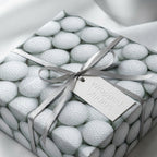 Golf ball wrapping paper on a gift box with silver ribbon bow and Wrapped Studios tag.