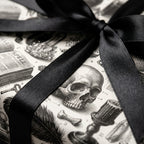 Gothic skull wrapping paper with black satin ribbon, spooky Halloween gift wrap by Wrapped Studios.