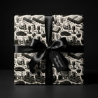 Gothic skull wrapping paper with black satin bow, luxury dark academia gift wrap by Wrapped Studios.