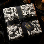 Gothic dark academia wrapping paper with skulls, tied with a black ribbon from Wrapped Studios.
