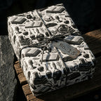Gothic wrapping paper with vintage skull and spellbook pattern, tied with twine by Wrapped Studios.