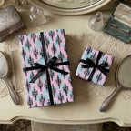 Pastel goth wrapping paper with black ribbons on a vintage vanity. Luxury gift wrap by Wrapped Studios.