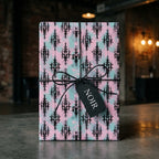 Pastel goth wrapping paper in pink and mint green damask design by Wrapped Studios, tied with black twine.