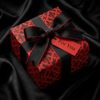 Luxury red and black gothic wrapping paper with ribbon bow and gift tag on satin by Wrapped Studios.