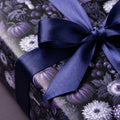 Gothic purple floral wrapping paper with pumpkins and a navy satin ribbon bow by Wrapped Studios.