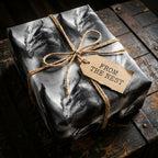 Fantasy dragon wrapping paper on a gift box with a twine bow on a rustic wooden chest, by Wrapped Studios.