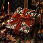 Spooky gothic wrapping paper with skull pattern and orange velvet bow by Wrapped Studios.