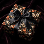 Gothic Halloween wrapping paper with skulls and pumpkins, tied with a black satin bow by Wrapped Studios.