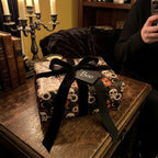 Gothic Halloween wrapping paper with skulls and pumpkins, tied with a black velvet bow by Wrapped Studios.