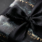 Wrapped gift with black ribbon and spooky Halloween themed wrapping paper.